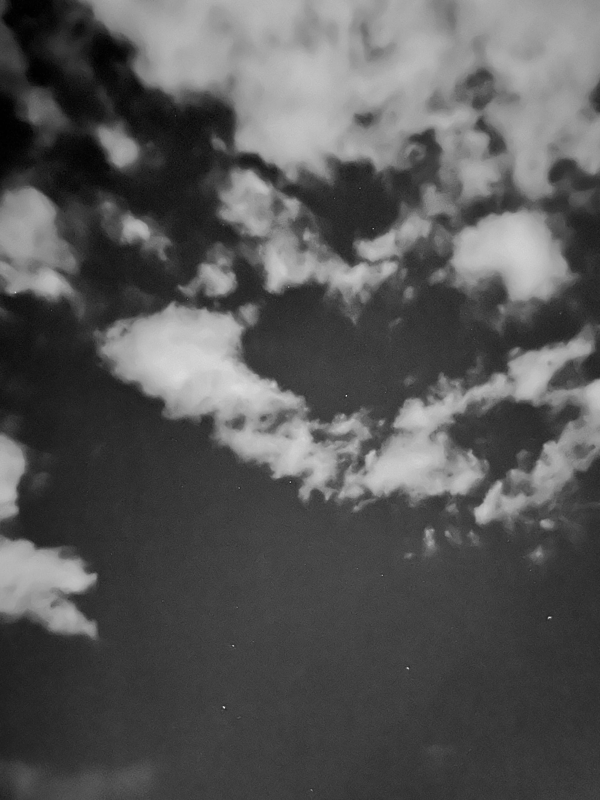 Ein schwarzweißer Nachthimmel, man sieht Sterne wie Punkte leuchten, weiße Wolken schweben. (C) Herr Montag.