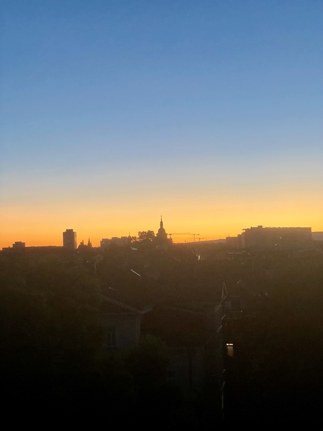 Der Sonnenaufgang über der Stadt, der Himmel ist unglaublich orange und blau.